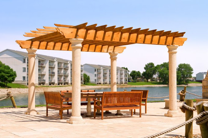 Timber pergola with stone columns beside a lake