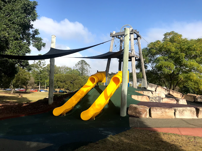 Yellow slides at a shaded playground in Queens Park