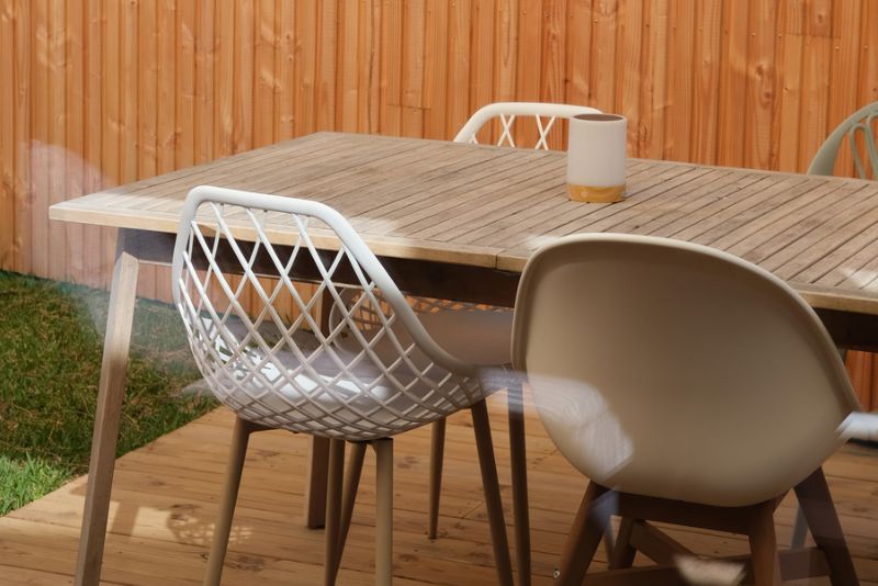Close-up of a coffee mug on an outdoor table with mesh-back chairs