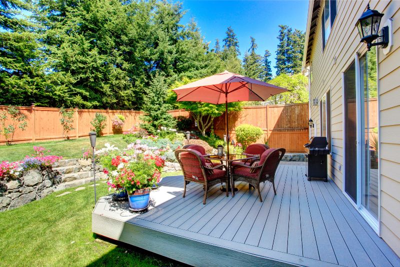 Composite deck with an umbrella-shaded dining table and wicker chairs