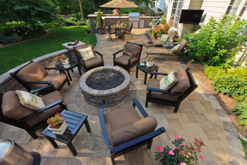 Stone patio with lounge seating arranged around a fire pit