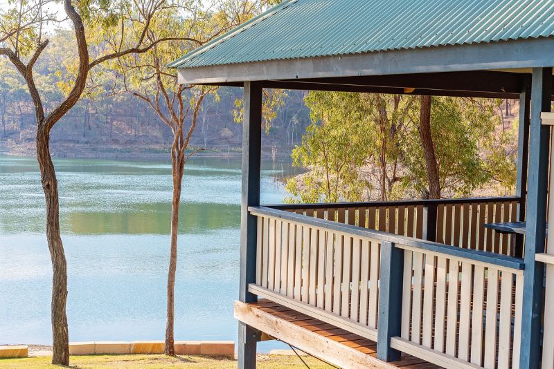 Timber verandah with a green roof overlooking a lake, surrounded by gum trees